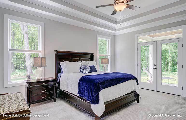The primary bedroom features dark wood furnishings and a french door leading to the rear porch.