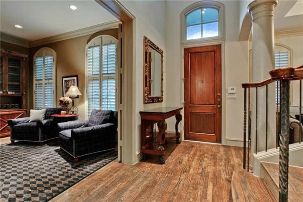 The foyer has an arched transom and a dark wood console table topped with a decorative mirror.