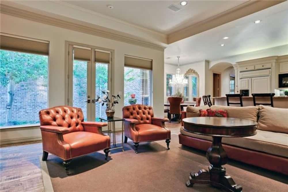 Family room with a leather sofa, tufted armchairs, and a round table over a bordered area rug.