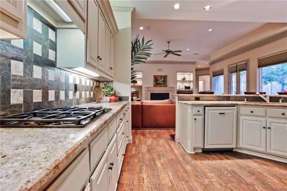 Kitchen with white cabinets, granite countertops, and a built-in cooktop.