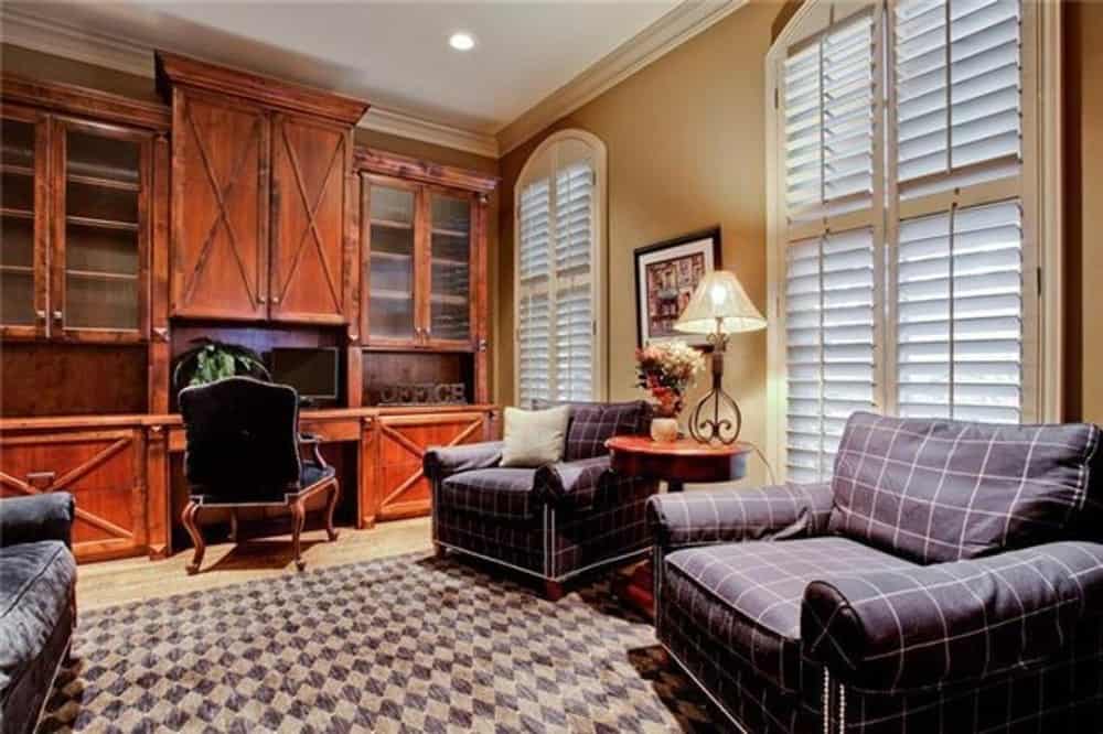 Living room with plaid armchairs and a built-in desk topped with overhead cabinets.