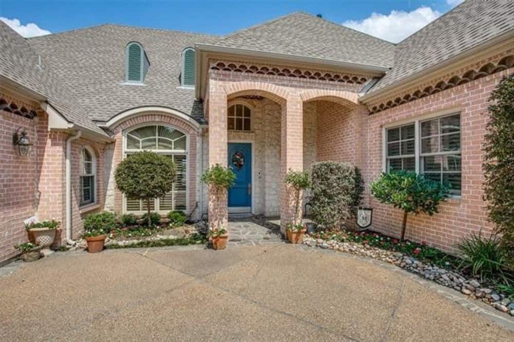 The home entry has a covered porch with a blue front door and tall archways.