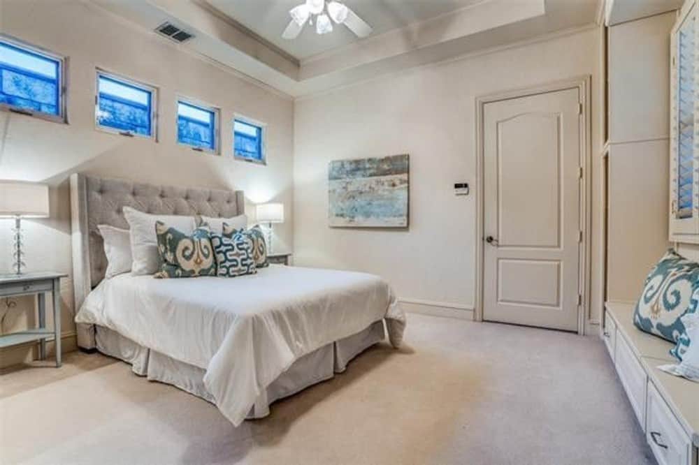 Primary bedroom with a built-in bench and a tufted wingback bed topped with small windows.
