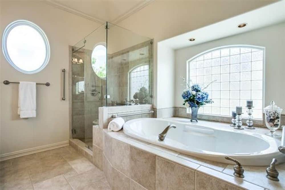Round and arched windows bring natural light into the primary bathroom.