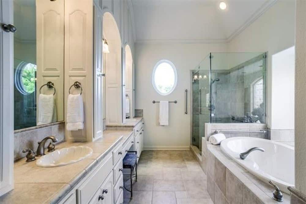The primary bathroom offers a drop-in bathtub, a walk-in shower, and a dual sink vanity with a make-up counter in the middle.