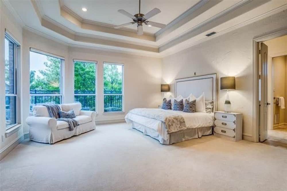 A stunning step ceiling mounted with a fan crowns the primary bedroom.