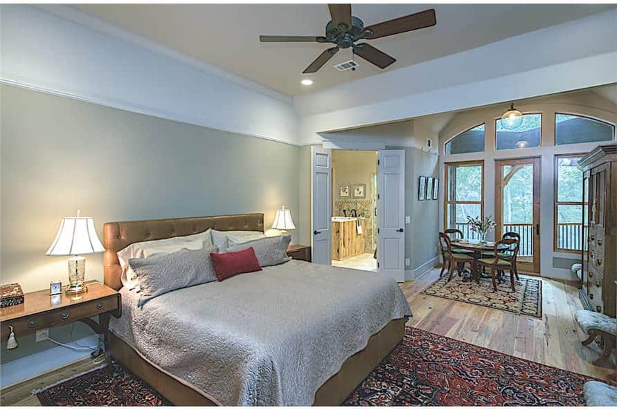 Primary bedroom with a leather upholstered bed and a spacious sitting area that extends onto the balcony.