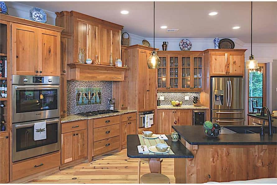The kitchen is equipped with stainless steel appliances, wooden cabinetry, a built-in cooktop, and a kitchen island incorporated with an eating bar.
