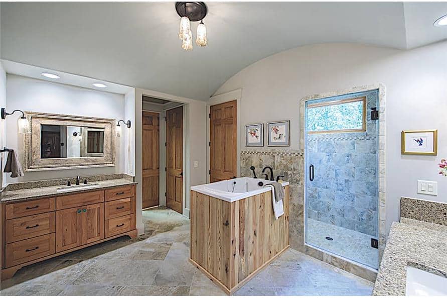 The primary bathroom has his and her sink vanities, a walk-in shower, and a deep soaking tub under the barrel-vaulted ceiling.