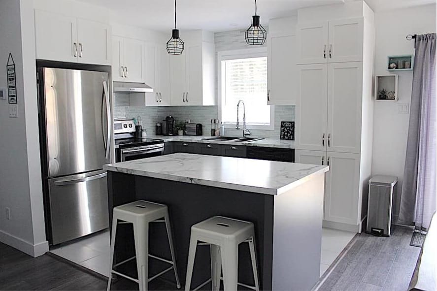 The kitchen is equipped with stainless steel appliances, white cabinetry, and a center island paired with sleek bar stools.