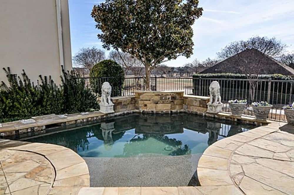 A closer look at the swimming pool adorned with statues and decorative pots.