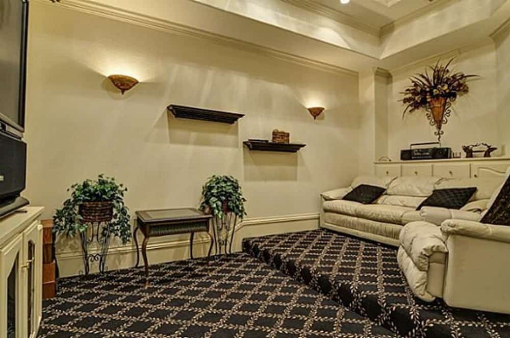 Media room with leather recliners, white cabinets, and a classic table over the patterned carpet flooring.