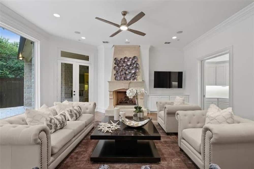 Living room with classy tufted seats, a wooden coffee table, and a fireplace graced with wall art.