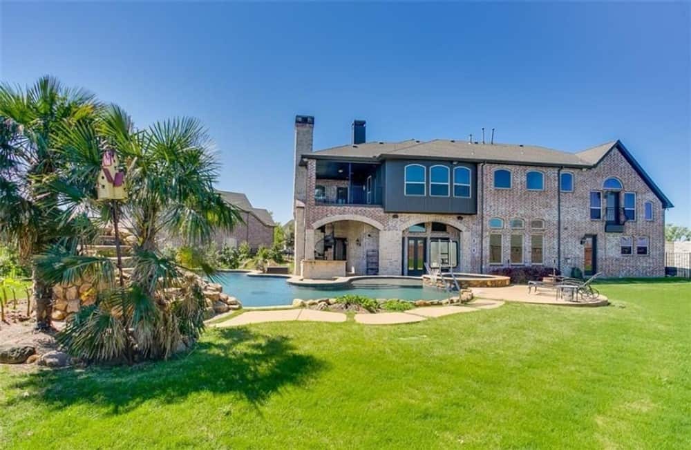 View of the house from the backyard showing the covered porch and pool terrace.