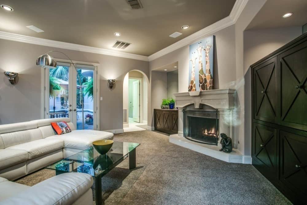 Family room with a fireplace and a white leather sectional paired with a glass top coffee table.