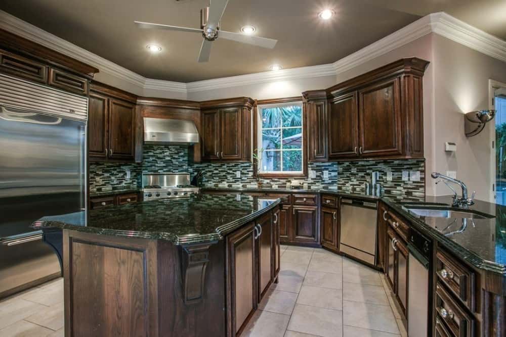 Kitchen with dark wood cabinetry, linear mosaic tile backsplash, and a large center island.