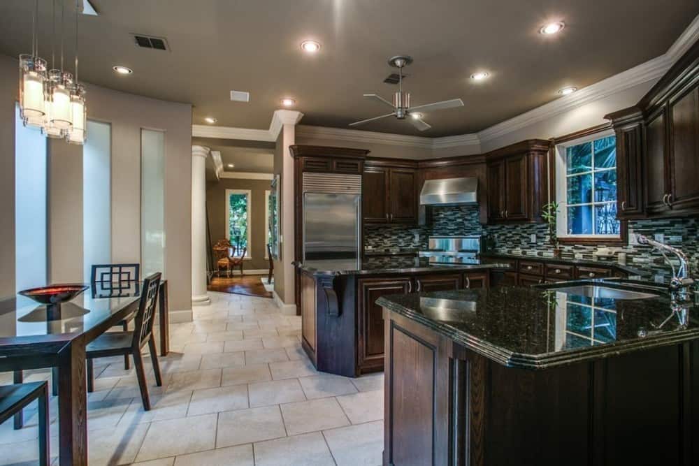 The kitchen includes an adjoining breakfast nook illuminated by cylindrical glass pendants.