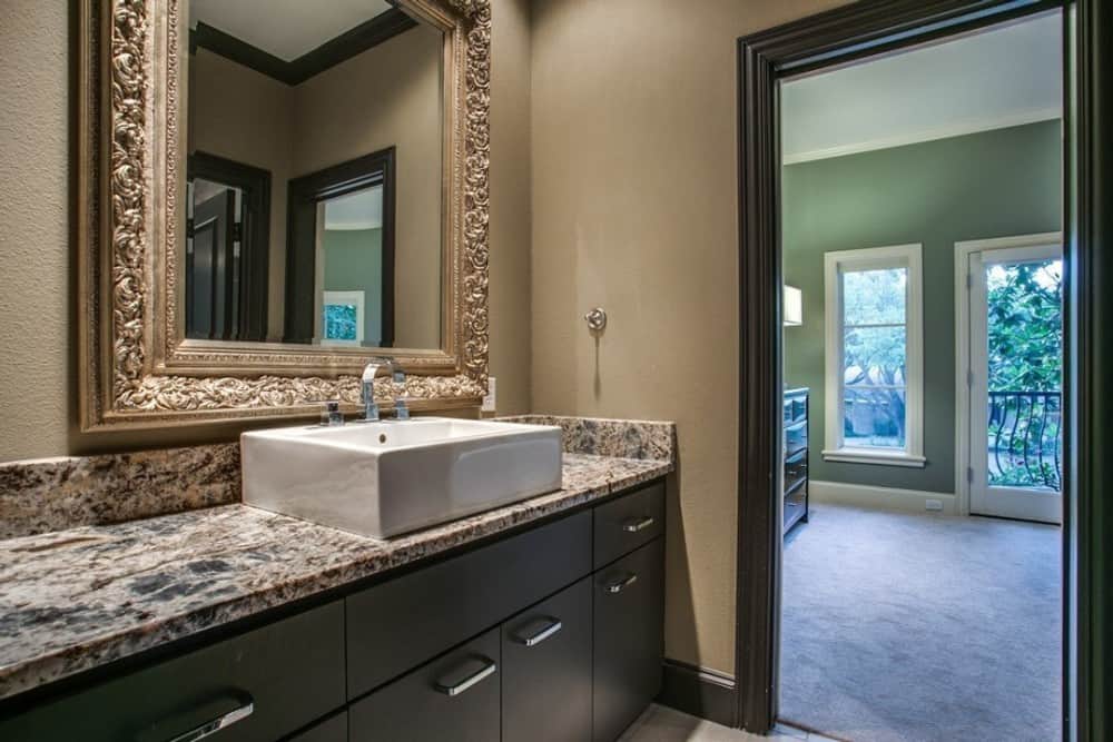 This bathroom offers a vessel sink vanity paired with a large, ornate mirror.