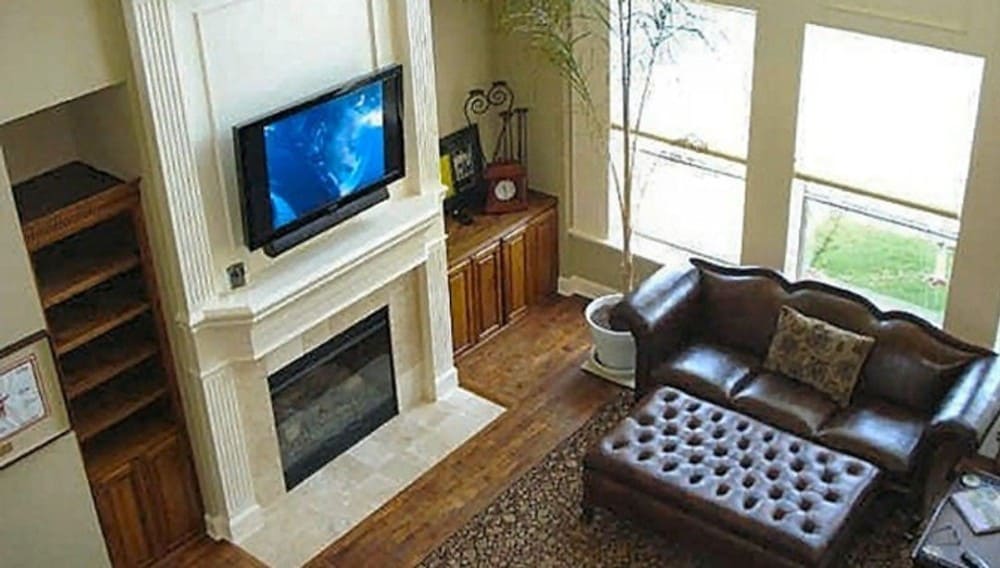 View of the family room from the second level balcony showing its high ceiling and large windows that bring ample natural light in.
