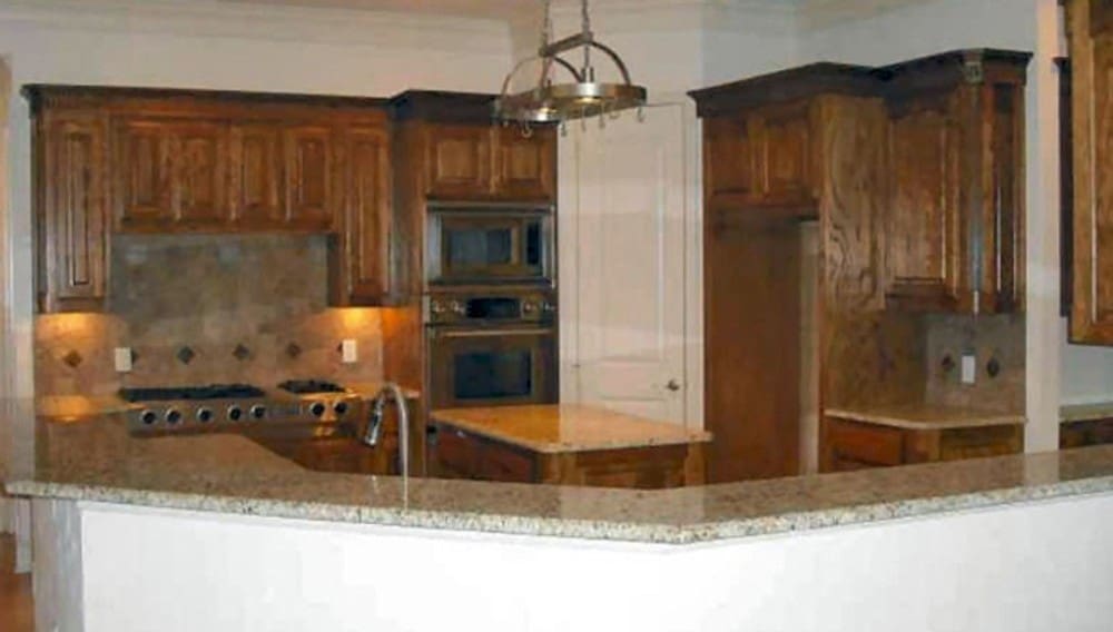 The kitchen includes wooden cabinetry and a center island topped with a hanging chrome pot rack.