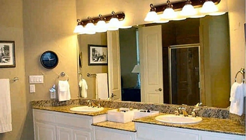 The primary bathroom features a granite top vanity with double sinks, a makeup counter, and a large frameless mirror.