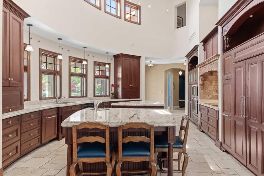 The kitchen is spacious and offers two islands, wooden cabinetry, a cooking alcove, and clerestory windows. Image courtesy of Toptenrealestatedeals.com.