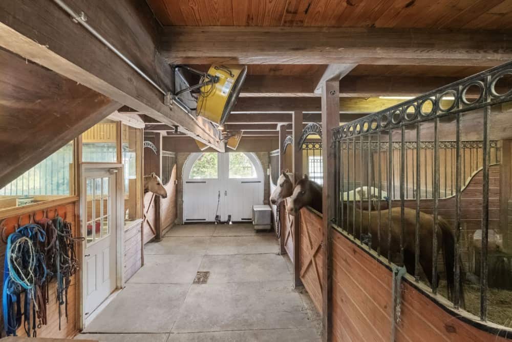 Barn's interior with spacious stables under a beamed ceiling. Image courtesy of Toptenrealestatedeals.com.