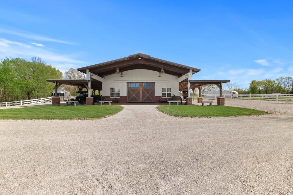 Equestrian barn with white siding and covered porches. Image courtesy of Toptenrealestatedeals.com.