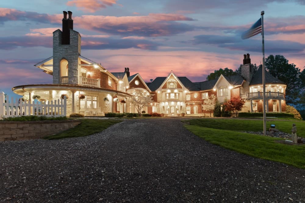 Night view of the mansion showcasing its warm ambient glow complementing the brick exterior. Image courtesy of Toptenrealestatedeals.com.