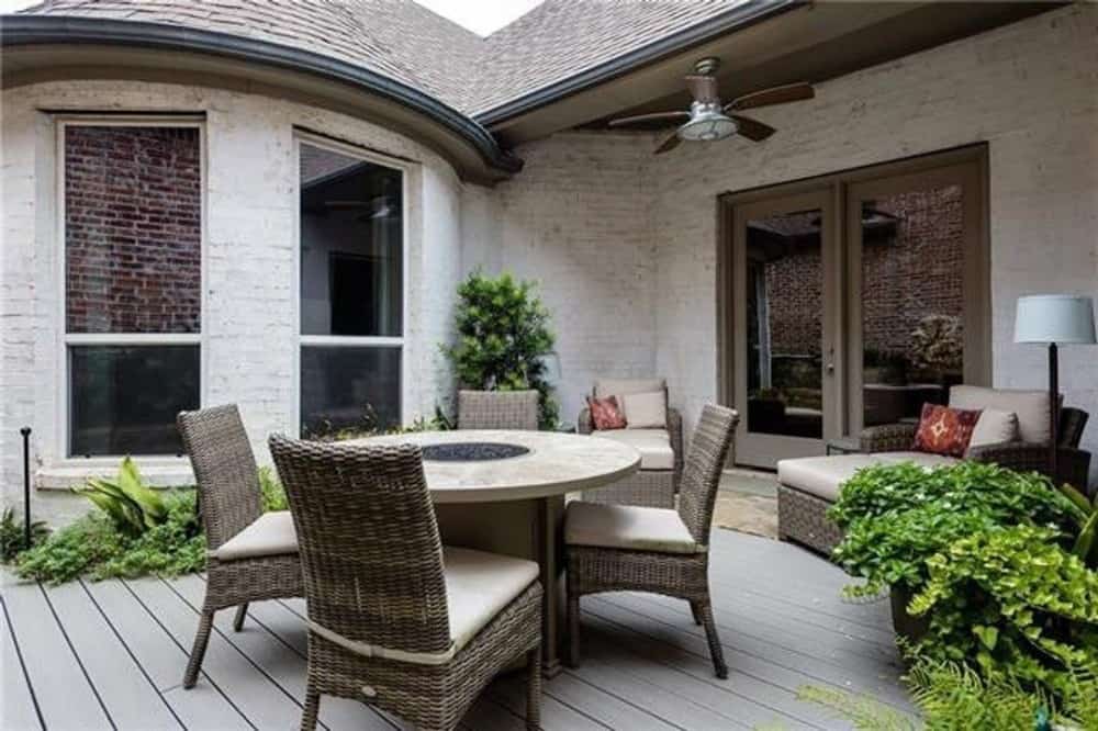 Patio with wicker loungers and a deck furnished with a round dining set.