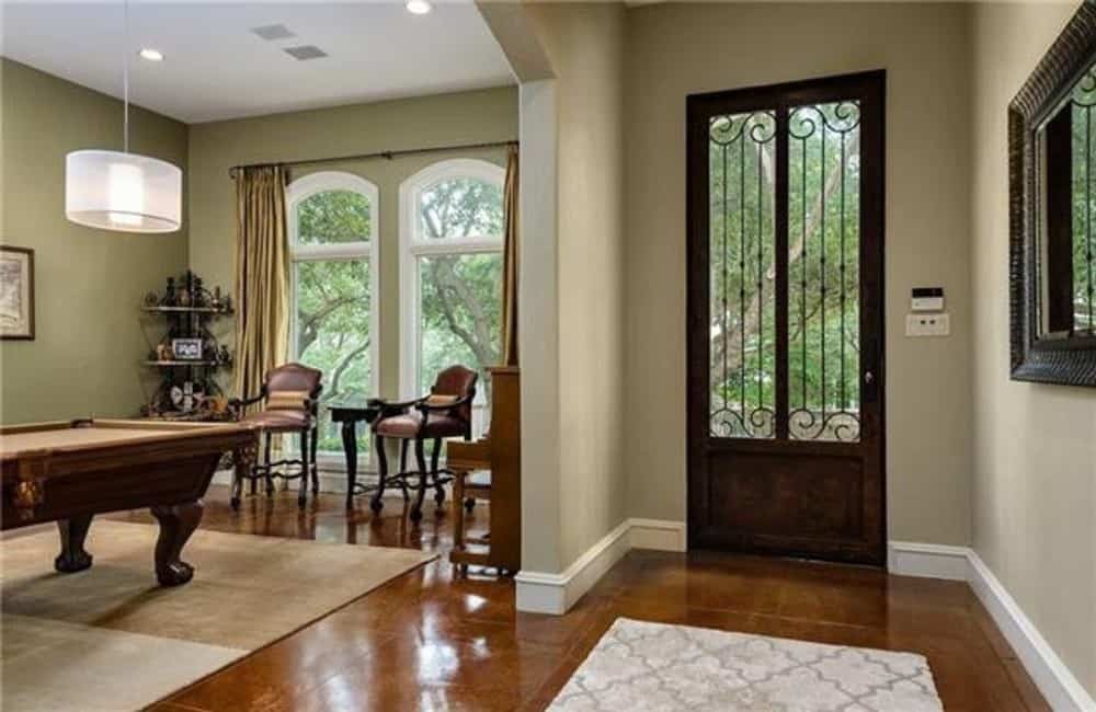 Foyer with a glazed entry door, a patterned rug, and a large decorative mirror gracing the beige walls.