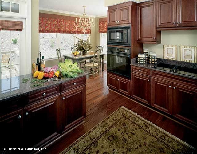 The kitchen is equipped with black appliances, dark wood cabinetry, granite countertops, and an adjoining breakfast nook.
