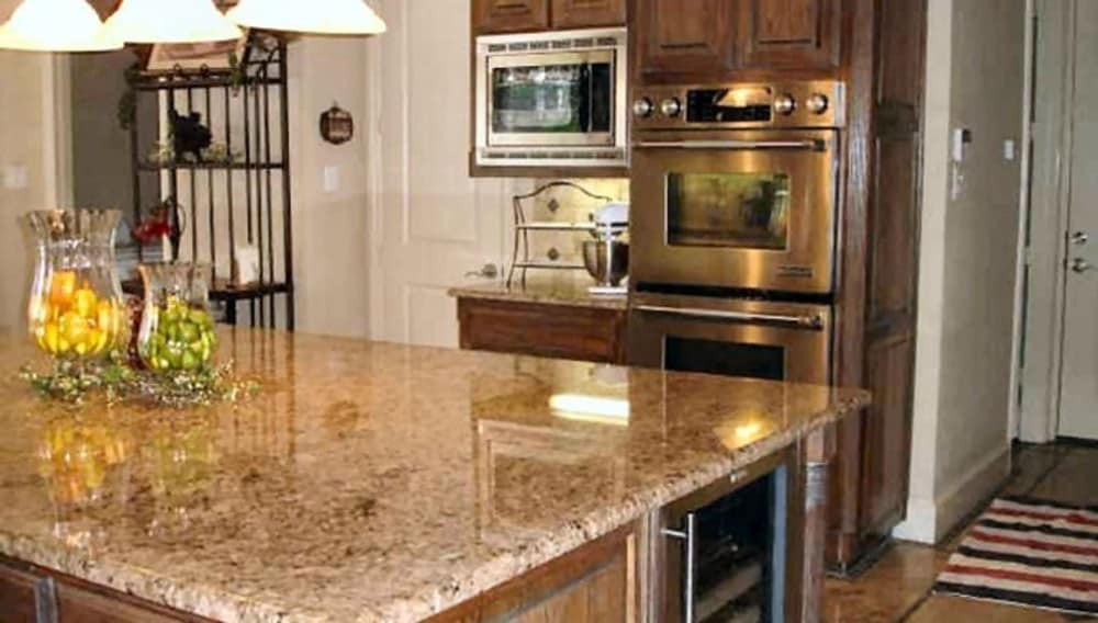 The kitchen is equipped with stainless steel appliances, granite countertops, wooden cabinetry, and a large center island.