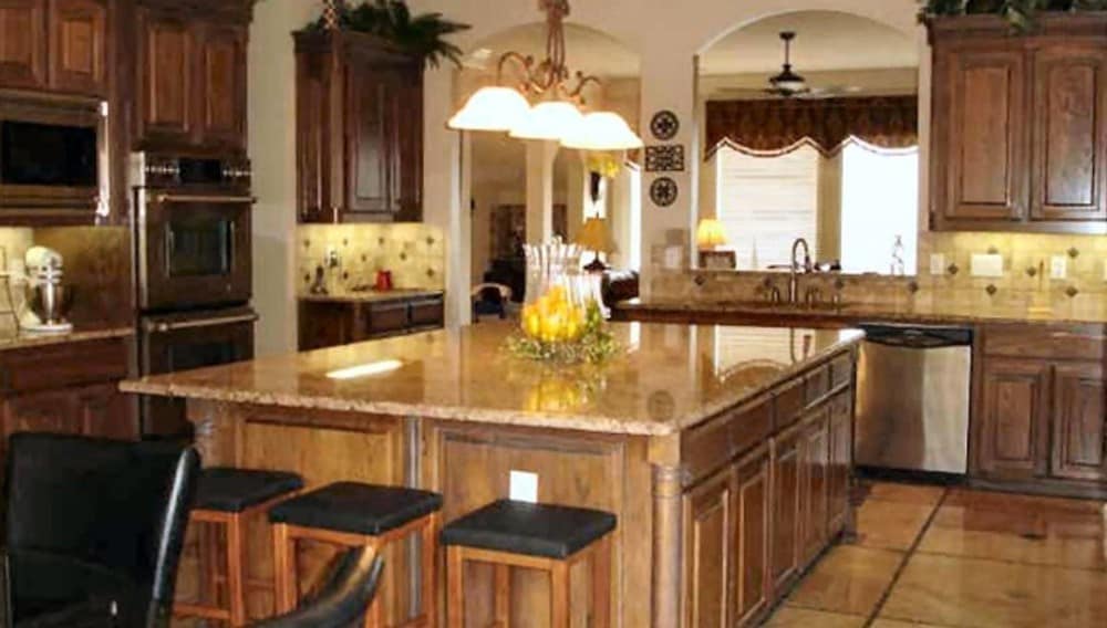 Three bar stools and warm glass dome pendants complement the large island.
