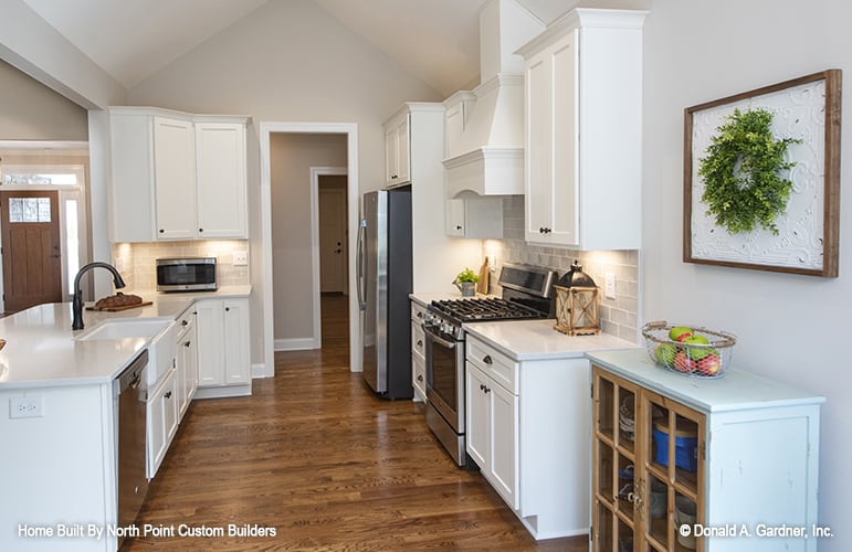 Kitchen with white cabinetry, stainless steel appliances, and a breakfast bar fitted with a farmhouse sink.
