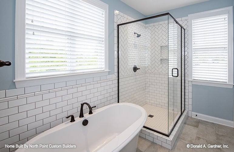 Primary bathroom with a walk-in shower and a freestanding tub fitted with wrought iron fixtures.