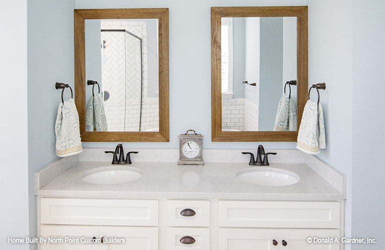 The primary bathroom includes a dual sink vanity paired with a couple of wooden framed mirrors.