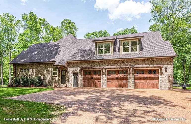 Right exterior view featuring a three-bay garage topped with twin shed dormers.