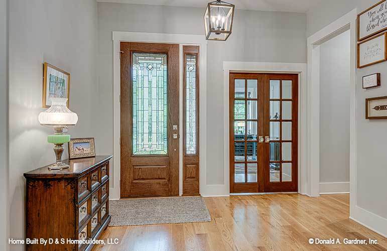 The foyer has a caged pendant and a wooden console table topped with a framed photo and a table lamp.