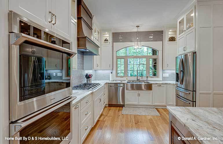 The kitchen includes stainless steel appliances, and a farmhouse sink fixed under the arched window.