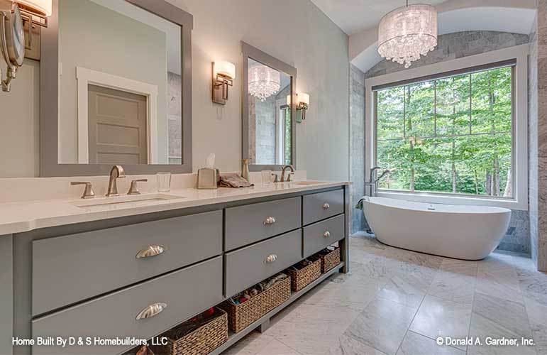 Primary bathroom with dual sink vanity and a freestanding tub illuminated by a classy drum pendant along with natural light streaming in from the large picture window.