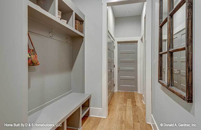 Mudroom with hanging shelves, wall hooks, and a built-in bench with storage underneath.