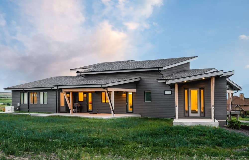 Rear exterior view showing the slant rooflines, dark horizontal siding, and expansive outdoor living.