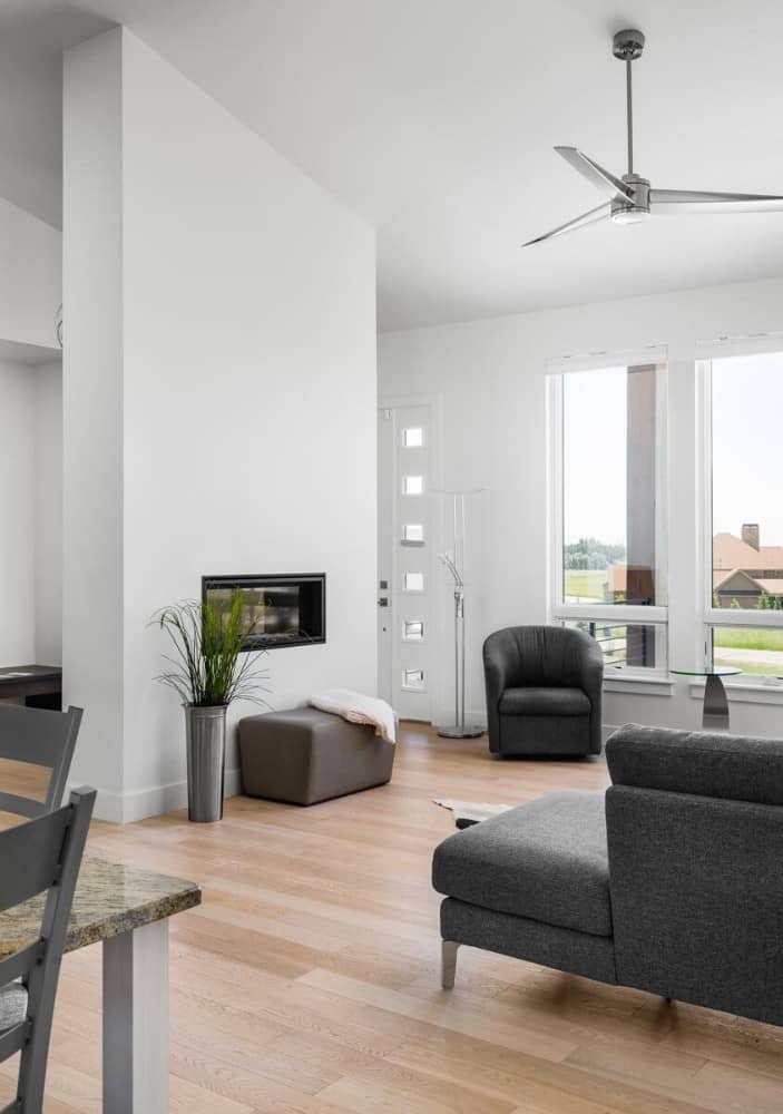 Living room with a double-sided fireplace and sleek gray seats over the light hardwood flooring.