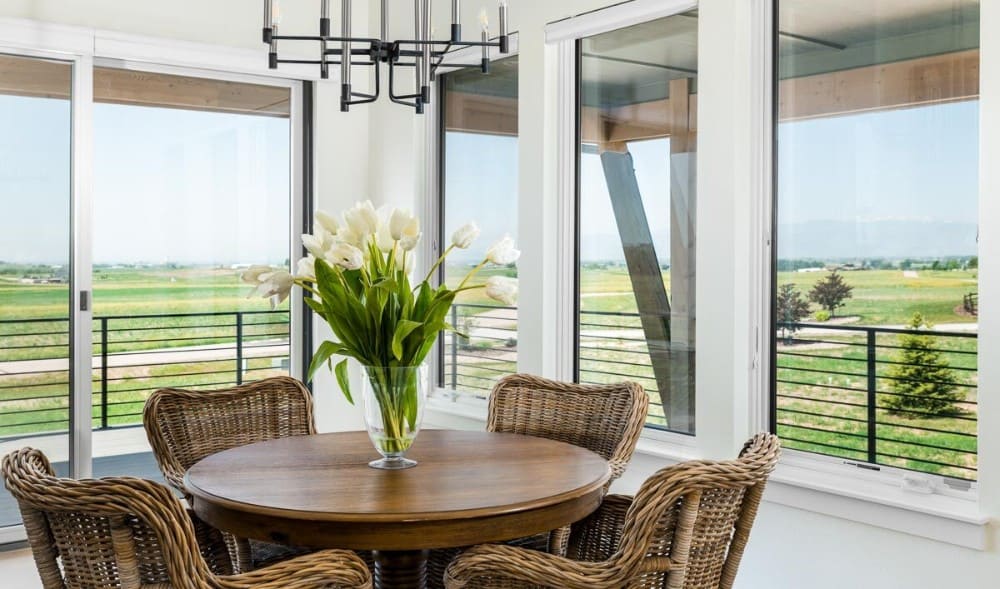 The dining room offers a round dining set, a contemporary chandelier, and sliding glass doors that open to the surrounding deck.