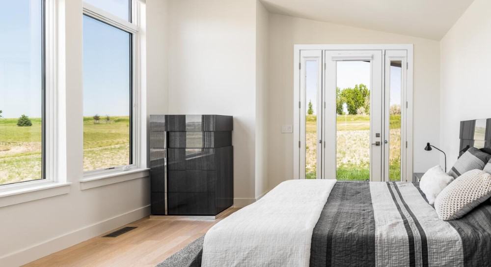 Primary bedroom with a sloped ceiling, a modern bed, and outdoor access through a glazed door.