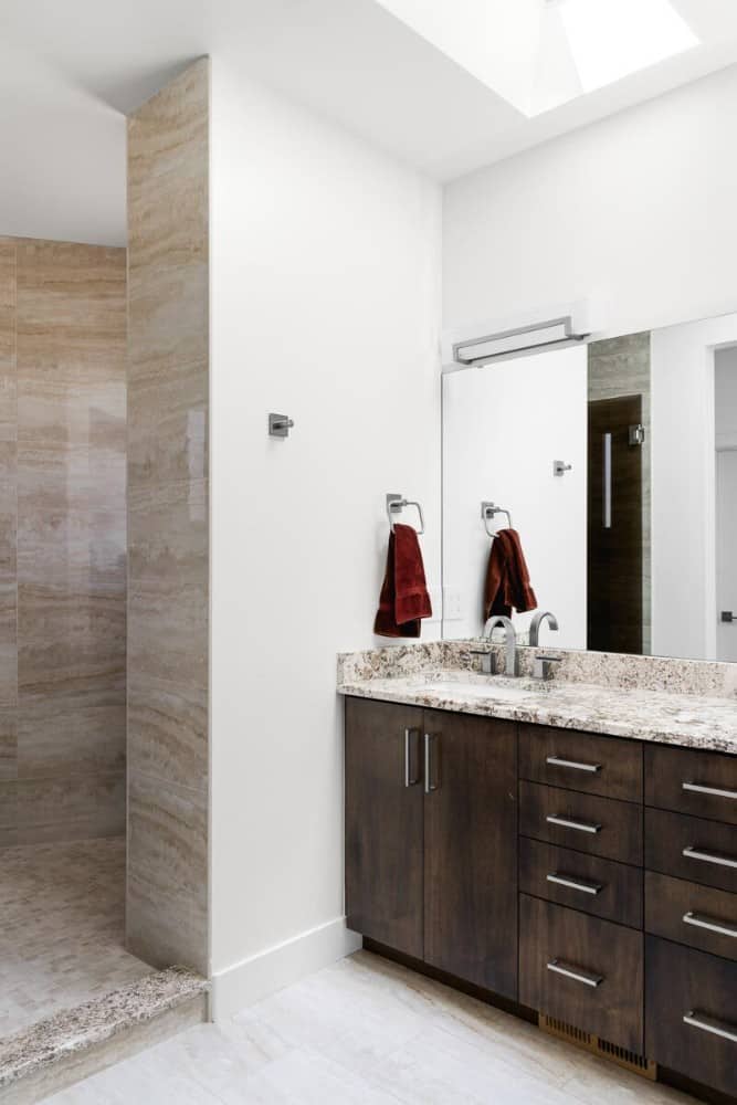 The primary bathroom includes a walk-in shower and a dual sink vanity paired with a large frameless mirror.