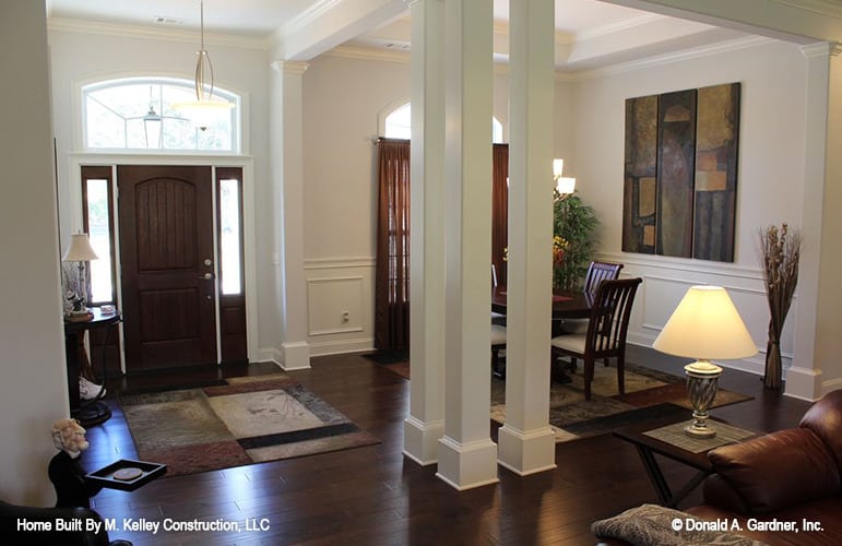 Foyer with white columns and a wooden entry door topped with an arched transom.