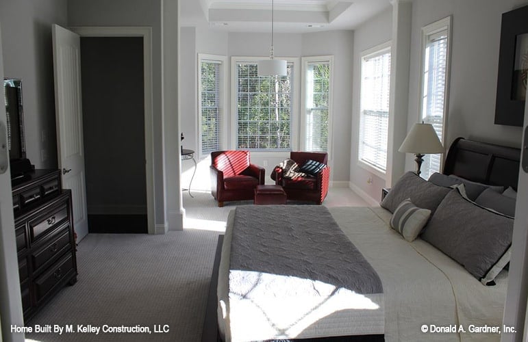 The primary bedroom includes a sitting area furnished with red leather armchairs and a matching ottoman.