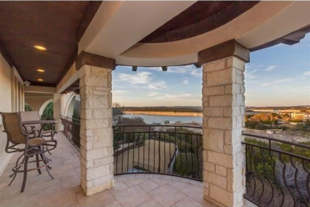 Covered balcony with stone columns and metal counter chairs that match the railings. It has a great view of the expansive surrounding.